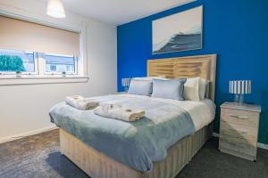 a blue bedroom with a large bed with towels on it at Sedgebank House in Livingston