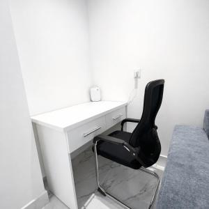 una sedia nera seduta di fronte a una scrivania bianca di Najd Cozy Apartment a Dammam