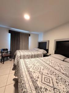 马塔莫罗斯Hotel Ossi Inn的有两张床和一把椅子的酒店房间