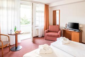 a hotel room with a bed and a chair and a window at Vitalhotel Weisse Elster in Bad Elster