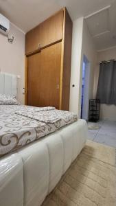 una camera da letto con un grande letto bianco con testiera in legno di Bienvenue chez vous a Libreville