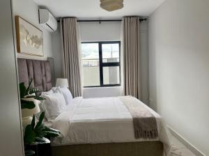 a bedroom with a white bed and a window at Cozy Habitat in Gaborone +6 photos