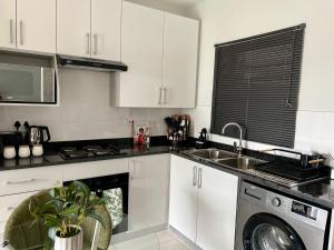 a kitchen with white cabinets and a sink and a dishwasher at Cozy Habitat in Gaborone