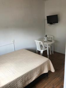 een slaapkamer met een bed, een tafel en een tv bij Departamentos LT3 in Las Toscas