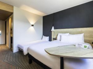 a hotel room with two beds and a table at Ibis Styles Crolles Grenoble A41 in Crolles