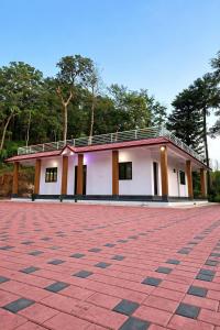 a building with a red brick driveway in front of it at Dream Garden Homestay in Madikeri