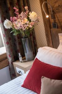a bed with a vase of flowers next to a window at Le Cristal de Jade in Chamonix
