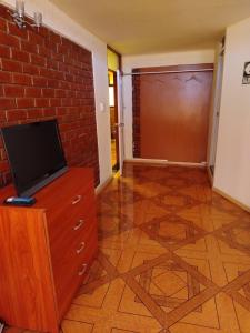 een woonkamer met een televisie en een bakstenen muur bij Asvea INN in Arequipa