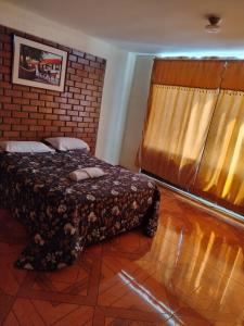 een slaapkamer met een bed en een bakstenen muur bij Asvea INN in Arequipa