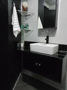 een zwart-witte badkamer met een wastafel en een spiegel bij Vanilla Lee Corporate Suite in Richards Bay