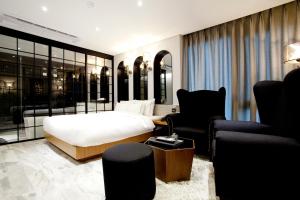 首爾的住宿－福達酒店，一间卧室配有一张床、一张沙发和椅子