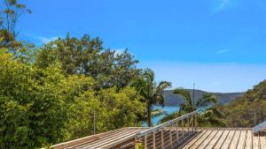 une terrasse avec vue sur l'eau et les arbres dans l'établissement Mountain Breeze, à Umina