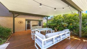 une terrasse en bois avec une table et des chaises. dans l'établissement Mountain Breeze, à Umina