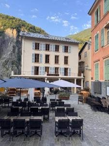 a hotel with tables and umbrellas in a courtyard at Le Touring in Isola