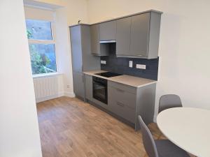 een keuken met grijze kasten en een tafel met stoelen bij 2 Bed Apartment with Harbour Views Apt 2 in Cobh