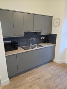 een keuken met witte kasten en een spoelbak bij 2 Bed Apartment with Harbour Views Apt 2 in Cobh