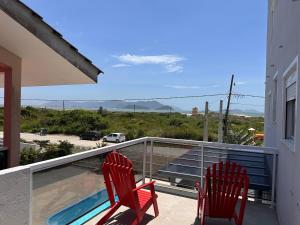 - deux chaises rouges assises sur le balcon d'une maison dans l'établissement Villa Cavaliere, à Palhoça