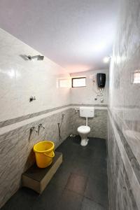 a bathroom with a toilet and a yellow bucket at Dream Garden Homestay in Madikeri