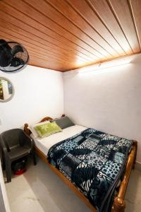 a small bedroom with a bed and a chair at Dream Garden Homestay in Madikeri
