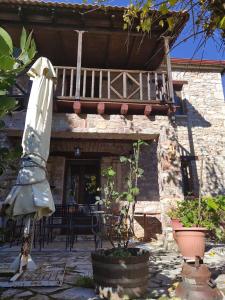 a building with a balcony and a table and an umbrella at Kleitor Stone Villa-Peloponnese Getaway in Klitoria