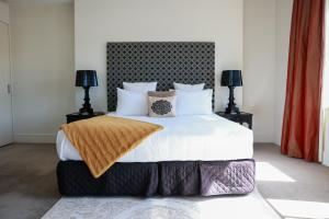a bedroom with a large white bed with two lamps at The Dome Boutique Apartments in Napier