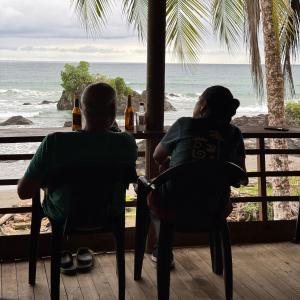 Due persone sedute a un tavolo che guardano l'oceano di Altos de la Playa a Bahía Solano