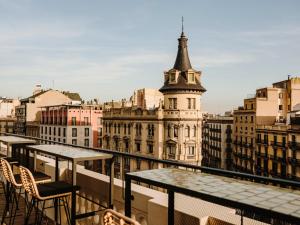 einen Balkon mit Tischen und Stühlen und Stadtblick in der Unterkunft Hotel Casa Luz in Barcelona