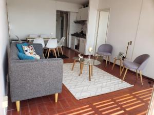 een woonkamer met een bank, een tafel en stoelen bij Departamento Concon Valparaíso in Concón