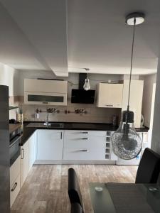 una cucina con mobili bianchi e un tavolo con sedie di Apartament EMA a Bistriţa