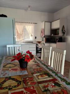 a kitchen with a table with red flowers on it at Casa do refúgio melhor para suas férias in Palhoça