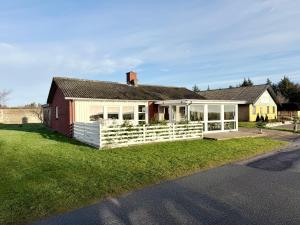 a house with a white fence in the grass at Amtoft Vig Kitespot in Vesløs