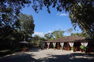 un pavillon avec des tables, des chaises et un parasol dans l'établissement Casa da Árvore - Pousada Jussara, à Joinville 22 autres photos