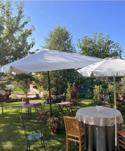 a white umbrella in a yard with tables and chairs at La Casa di Paolo in Battifollo