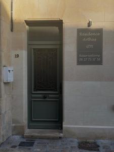 een groene deur aan de zijkant van een gebouw met een bord bij Résidence ARTHUS Thamarys in Pierrefonds