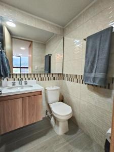 een badkamer met een toilet, een wastafel en een spiegel bij Cali - Apartaestudios Edificio Miro Living Guadalupe in Cali