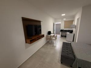 a living room with a television on a wall at Flats Privativos MaragoJulios in Maragogi