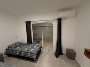een slaapkamer met een bed en een glazen schuifdeur bij Flats Privativos MaragoJulios in Maragogi