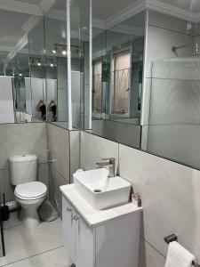 a bathroom with a sink and a toilet and mirrors at Malibu Dream in Gqeberha