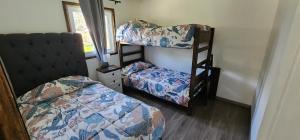 una stanza con tre letti a castello e una finestra di Cabañas Puelche a Liquiñe