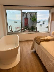 Morada Som do Mar في جوفيرنادور سيلسو راموس: حمام مع حوض وسرير ونافذة