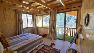a bedroom with a bed and a balcony with windows at Dar Aymane in Imlil