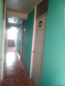 a hallway with green walls and a white door at Hospedaje Mis Sueños in San Antonio