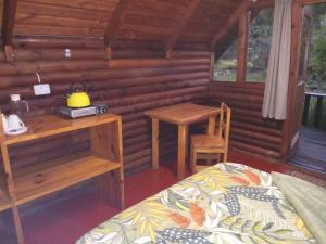 a bedroom of a log cabin with a bed and a desk at Tannenhof Countryside Log Cabins in Sanddrif