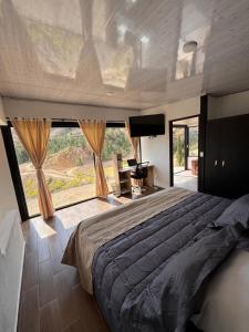 ein Schlafzimmer mit einem großen Bett und einem großen Fenster in der Unterkunft Glamping Eclipse Mirador Jarana Villa de Leyva 