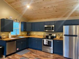 a kitchen with blue cabinets and stainless steel appliances at Sullivan Trail Cottage in Tannersville