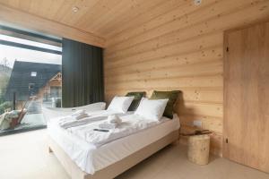 ein Bett in einem Zimmer mit einer Holzwand in der Unterkunft Jaszczurówka 33 Aparthotel & SPA in Zakopane