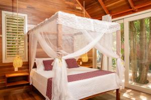 a bedroom with a canopy bed with curtains at Casa das Oliveiras Pipa in Pipa +46 photos