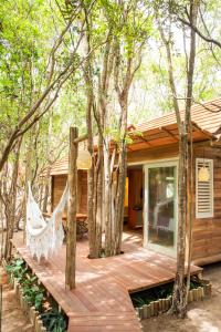 a wooden deck with a hammock in front of a house at Casa das Oliveiras Pipa in Pipa