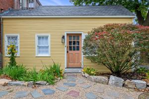 a yellow house with a wooden door in a yard at Broadway in Rockport