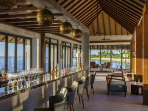 een restaurant met een bar met stoelen en tafels bij Pullman Maldives Maamutaa - All-Inclusive Resort - 50 percent off Domestic Transfers in Maamutaa